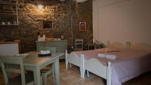 a bedroom with two beds and a table and a stone wall at Il Rifugio di Bomar in Pietrapertosa