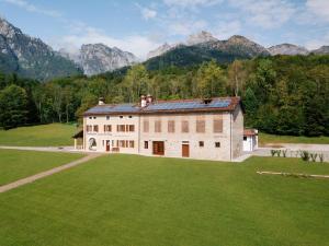 um grande edifício num campo com montanhas ao fundo em Fondazione Lucia De Conz 