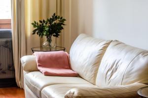 a white couch with a vase with a pink pillow at Bohemian Apartment - Center of Bucharest in Bucharest