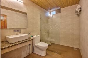 a bathroom with a toilet and a sink and a shower at Woodstock Inn Manali in Manāli