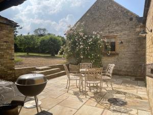 a patio with a grill and chairs and a building at The Studio in Castle Bytham