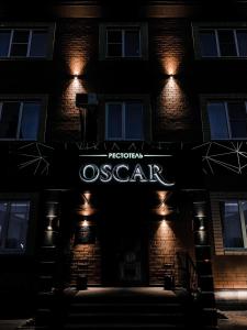 um sinal na lateral de um edifício à noite em Рестотель Oscar em Kursk