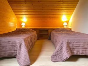 two beds in a room with wooden walls at Chalet Miel in Gérardmer
