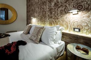 a bedroom with a bed with white pillows and a wall at Mercatovecchio Luxury Suites in Udine