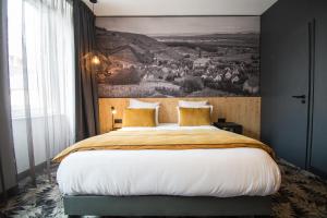 um quarto com uma cama grande e uma pintura na parede em L' Hôtel & Spa Ribeauville- Haut-Koenigsbourg em Ribeauvillé