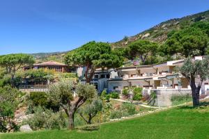 a house on a hill with trees in the foreground at Hotel Baia Imperiale in Campo nell'Elba