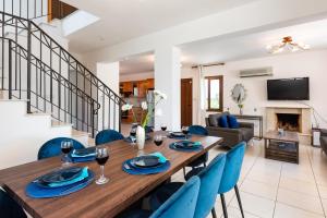 - une salle à manger et un salon avec une table en bois et des chaises bleues dans l'établissement Sea Front Costa Blu by Ezoria Villas, à Ayia Napa