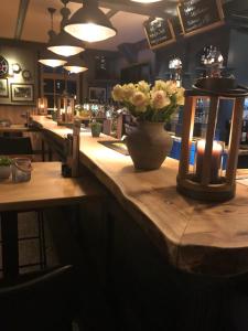 a bar with a table with a vase of flowers on it at Herberg Binnen in Egmond-Binnen