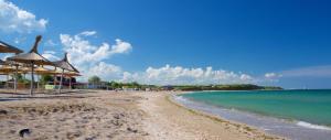 a sandy beach with umbrellas and the ocean at HOTEL BOURBON Vama Veche in Vama Veche