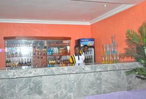 a bar with a man standing behind a counter at Room in Apartment - Sheriffyt Royale Hotel - Business Suite in Ikorodu