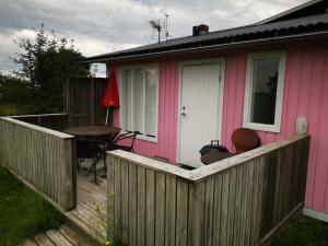 a pink house with a wooden deck with a table at Susanne's stugor Böda hamn in Böda