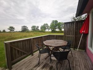 a wooden deck with a table and chairs on it at Susanne's stugor Böda hamn in Böda