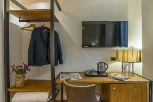 Navona Essence Hotel في روما: غرفة مع مكتب ومعطف معلق على رف