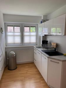 a kitchen with white cabinets and a trash can at Susewind in Bad Segeberg