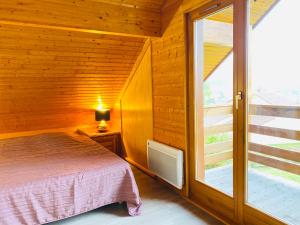 een slaapkamer met een bed en een groot raam bij Chalet Sapin in Gérardmer