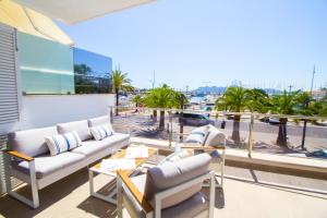 a balcony with couches and tables and palm trees at Chez Margaux, fantástico apartamento in Port de Pollensa