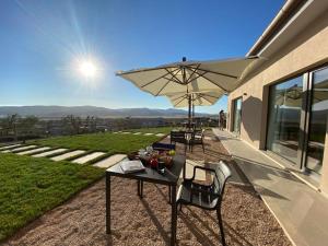 un patio con 2 mesas y una sombrilla blanca en Agriturismo La Vista - Adults Only, en Fonteblanda