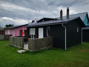 a black house with a fence and a yard at Susanne's stugor Böda hamn in Böda +27 photos