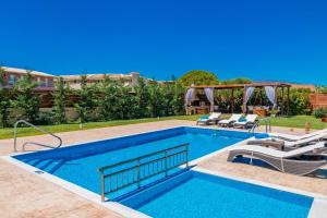una piscina con 2 tumbonas junto a ella en Villa Sophie - Sunny Retreat! en Kalamaki