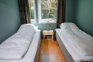 two beds in a room with a table and a window at Vestly in Etnesjøen
