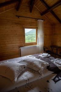 una camera da letto con un letto grande con una finestra di Pensiunea Farmecul Naturii și căsuțe individuale de închiriat Colibița a Colibiţa