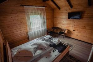 una camera da letto con un letto in una stanza di legno di Pensiunea Farmecul Naturii și căsuțe individuale de închiriat Colibița a Colibiţa