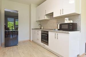 a kitchen with white cabinets and a microwave at Ritos Apartamentai Palangoje in Palanga