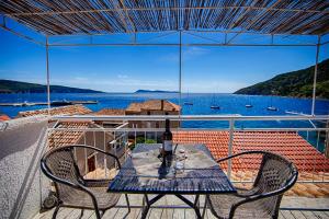 a table on a balcony with a view of the water at Komiza Provita Guesthouse in Komiža