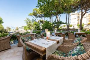 einen Holztisch mit Korbstühlen auf einer Terrasse in der Unterkunft Hotel Milton Rimini in Rimini