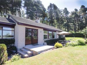 a small house with a patio and an umbrella at Culreach Lodge in Grantown on Spey