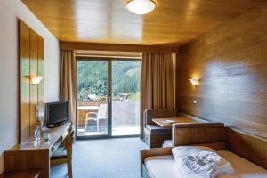 a hotel room with a bed and a desk and a table at Berghotel Tyrol in Senales