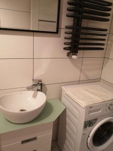 a bathroom with a sink and a washing machine at Apartamenty Jaskinia Solna in Ruda Śląska