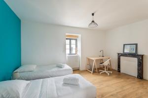 a bedroom with two beds and a desk with a table at Le Ty Family in Dinard
