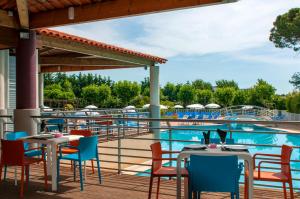 um pátio com mesas e cadeiras ao lado de uma piscina em Goélia Mandelieu Riviera Resort em Mandelieu-la-Napoule