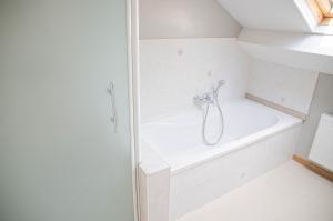 y baño blanco con bañera y ducha. en Le Moulin de Bosson - Une de Mai, en Ferrières