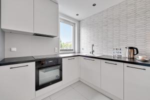 a white kitchen with white cabinets and a window at Comfort Apartments Navio in Gdańsk