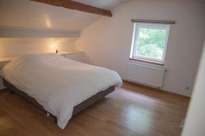 a bedroom with a white bed and a window at Le Moulin de Bosson - Une de Mai in Ferrières