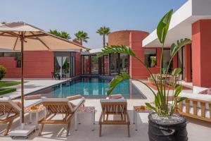 a resort with a swimming pool with chairs and an umbrella at Villa LOULA in Marrakesh