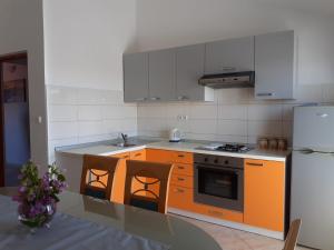 a kitchen with orange cabinets and a table and a refrigerator at Apartmani Sanda i Leo in Bibinje