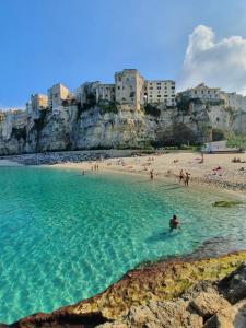 a beach with a group of people in the water at Tropea Home Free Private Parking in Tropea