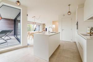 een keuken met witte werkbladen en een groot raam bij Renewed comfort duplex w 2 terraces nearby Marina in Nieuwpoort