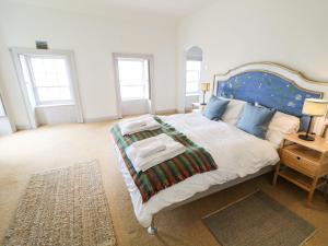 a bedroom with a large bed with a blue headboard at The Ferry House in Ramelton