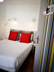 a bed with two red pillows in a room at The Bulldog Inn - Duna Parque Group in Vila Nova de Milfontes