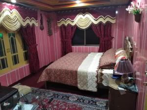 ein Schlafzimmer mit einem Bett in einem rosa Zimmer in der Unterkunft High Cliff Guest House in Khapalu