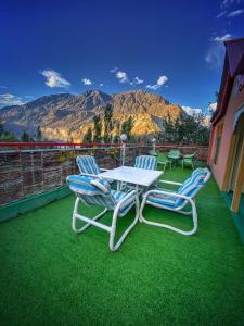 einen Tisch und zwei Stühle auf einem Balkon mit Bergblick in der Unterkunft High Cliff Guest House in Khapalu