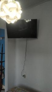 uma televisão pendurada numa parede com um lustre em Cozy House Booking Indaiatuba em Indaiatuba