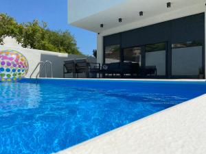 a swimming pool with a ball next to a house at Murter - Jezera Luxury Apartments in Jezera