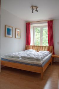 Cama en habitación con ventana roja en Apartmán ve SkiResortu Poustevník - Pec pod Sněžkou en Pec pod Sněžkou