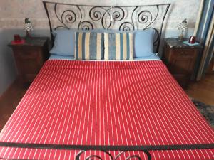 1 cama con colcha roja y 2 mesitas de noche en Il Melograno, en Borgo San Dalmazzo