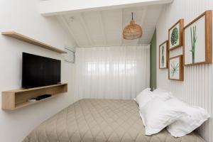 a bedroom with a bed with a flat screen tv at Apartamento Luxuoso à Beira-mar em Praia do Forte in Praia do Forte